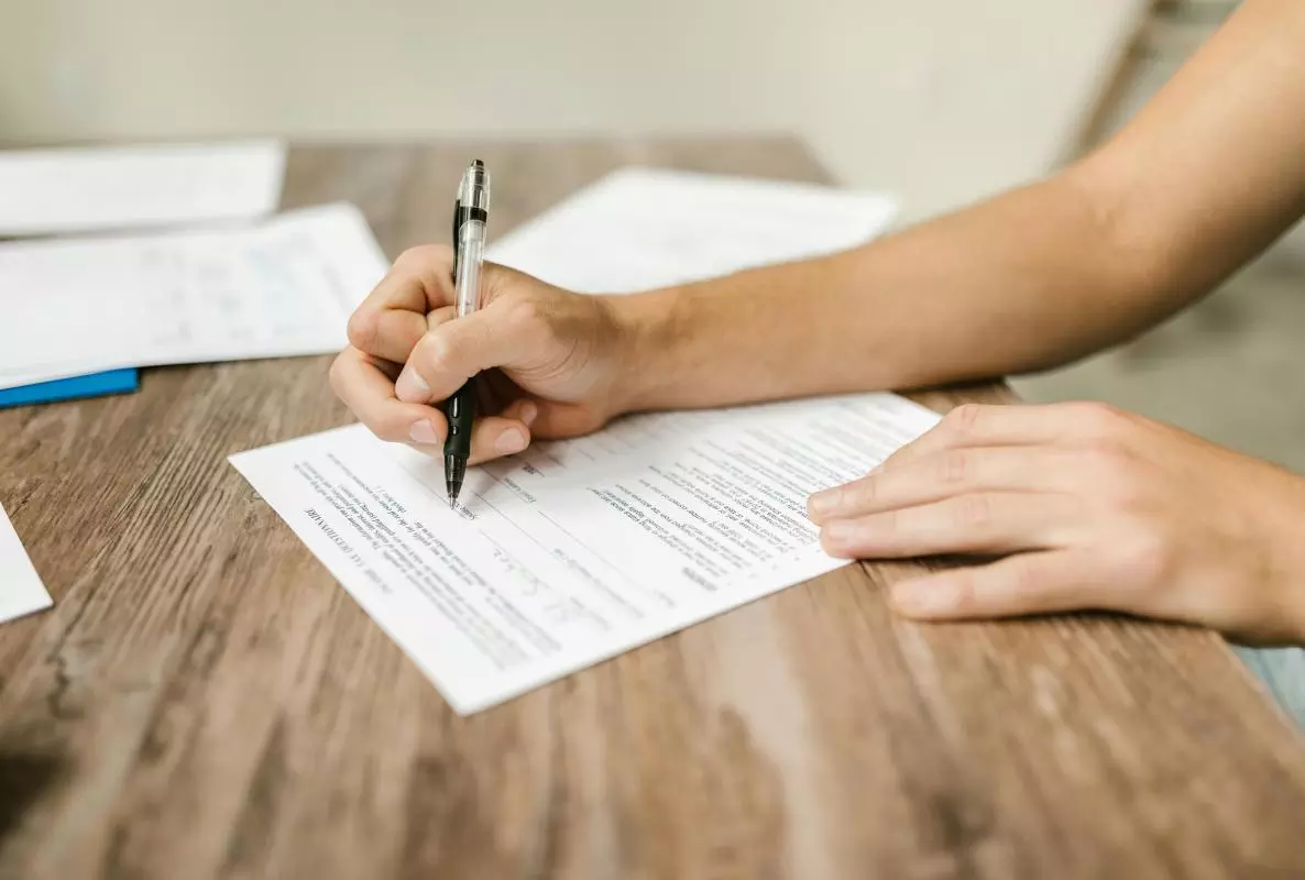 A close-up on the hand and forearm of a person filling in a paper questionnaire